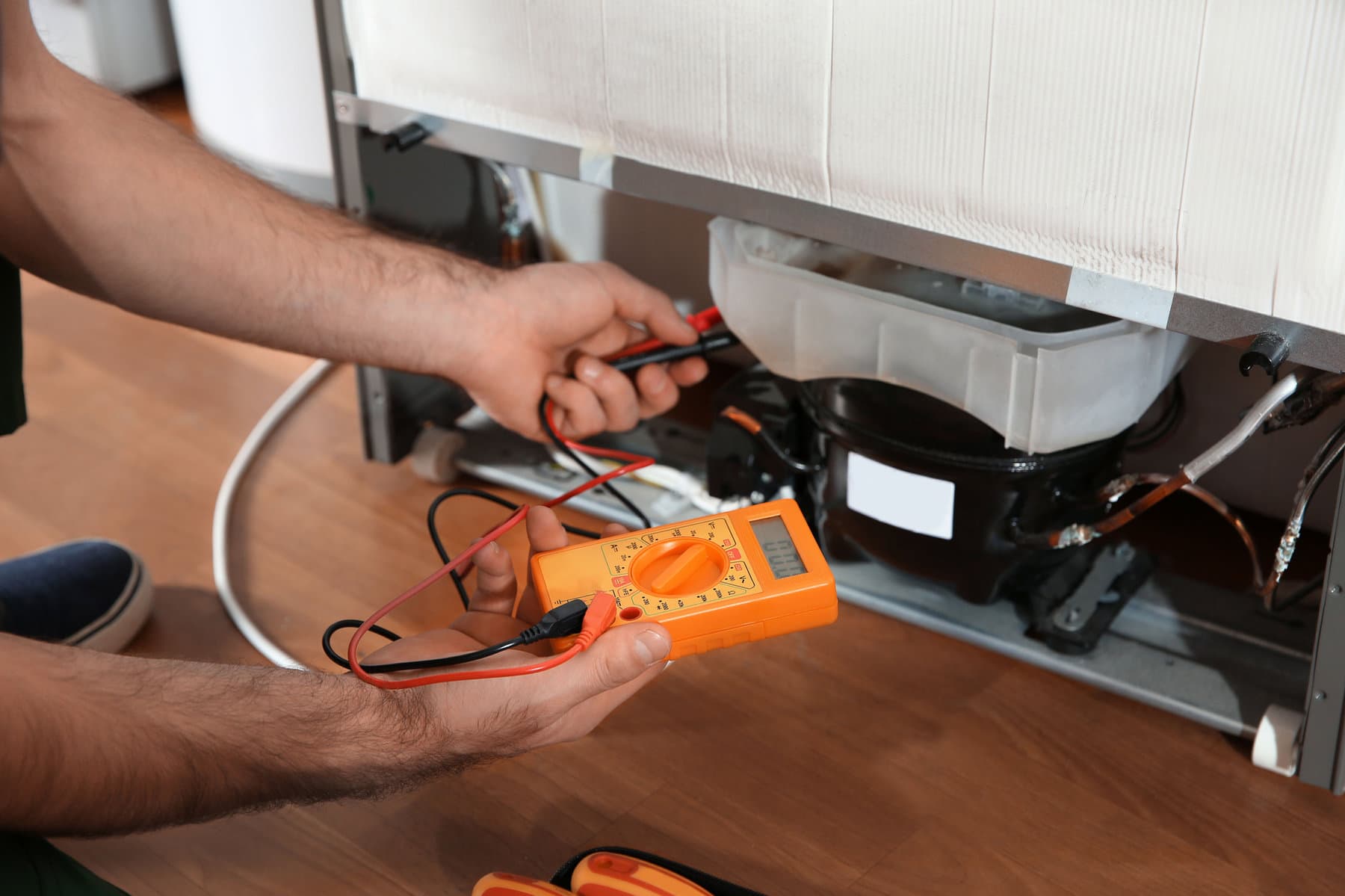 An engineer testing a fridge compressor with a multimeter